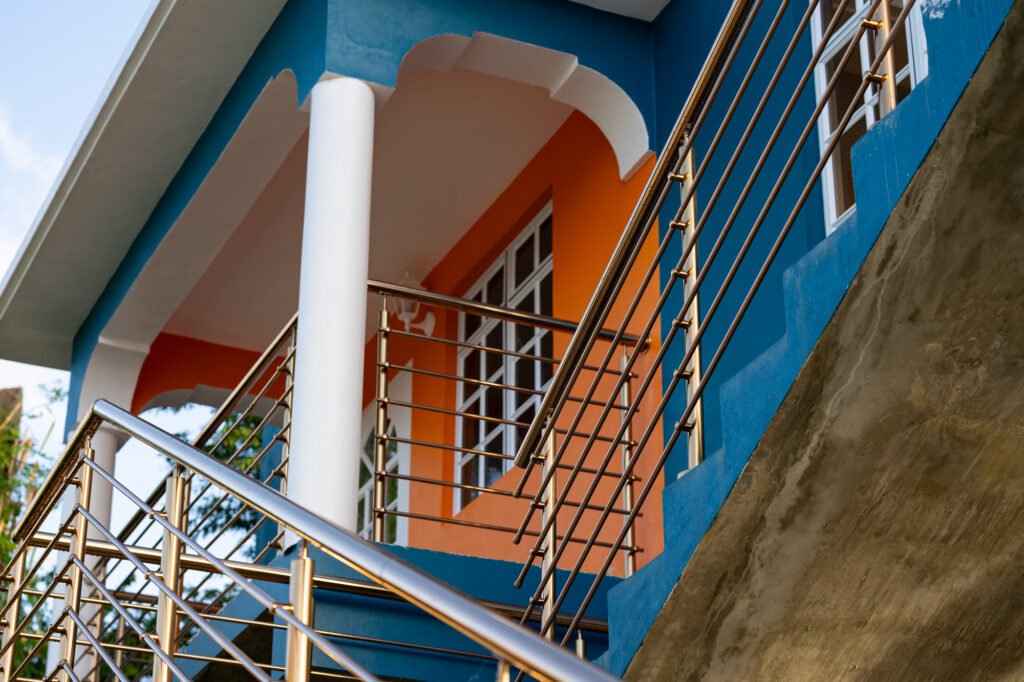 Stainless steel railing system installed on exterior staircase of a modern home in St Lucia with blue and orange walls.