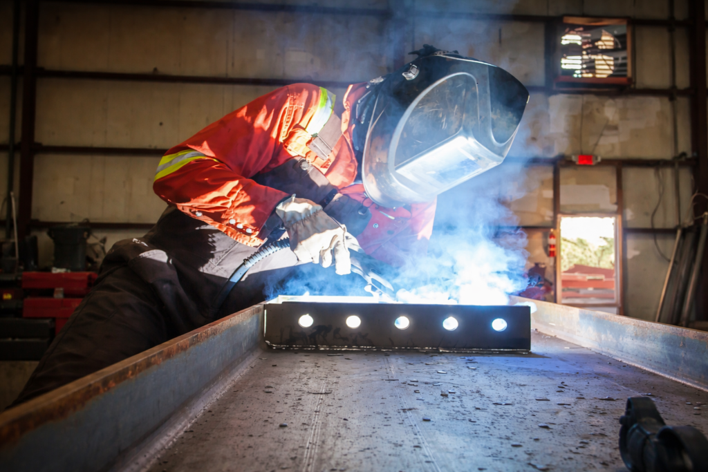 Home Welder performing precision welding on steel component in fabrication shop with bright arc and clean setup